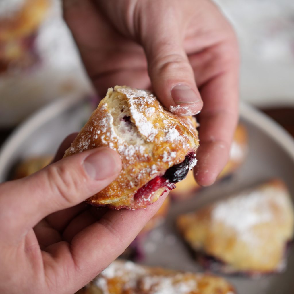 Breaking into a Easy Blueberry Turnover cutting it in half.
