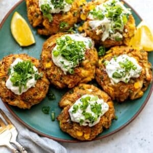 Maryland Crab Cakes on a green ceramic plate with two forks on the side and lemons.