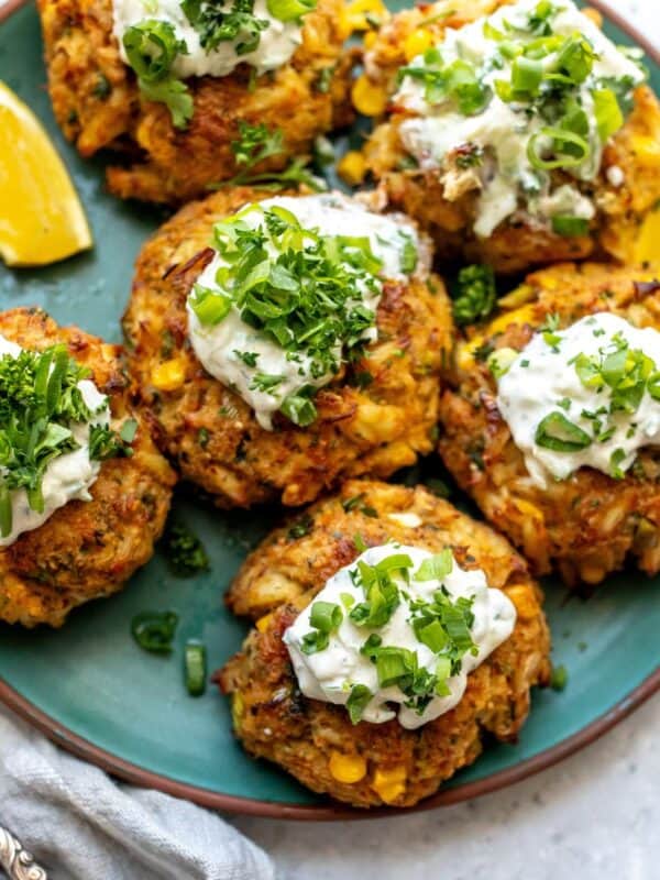 Maryland Crab Cakes on a green ceramic plate with two forks on the side and lemons.