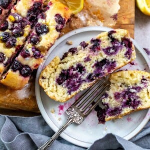 Lemon Blueberry bread with lemons on the side, one a plate with a silver fork.