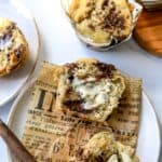 Chocolate Chunk Banana Muffins on a white ceramic plate with a butter knife to the side.