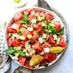 White bowl with ingredients mixed together to make watermelon salad with feta.