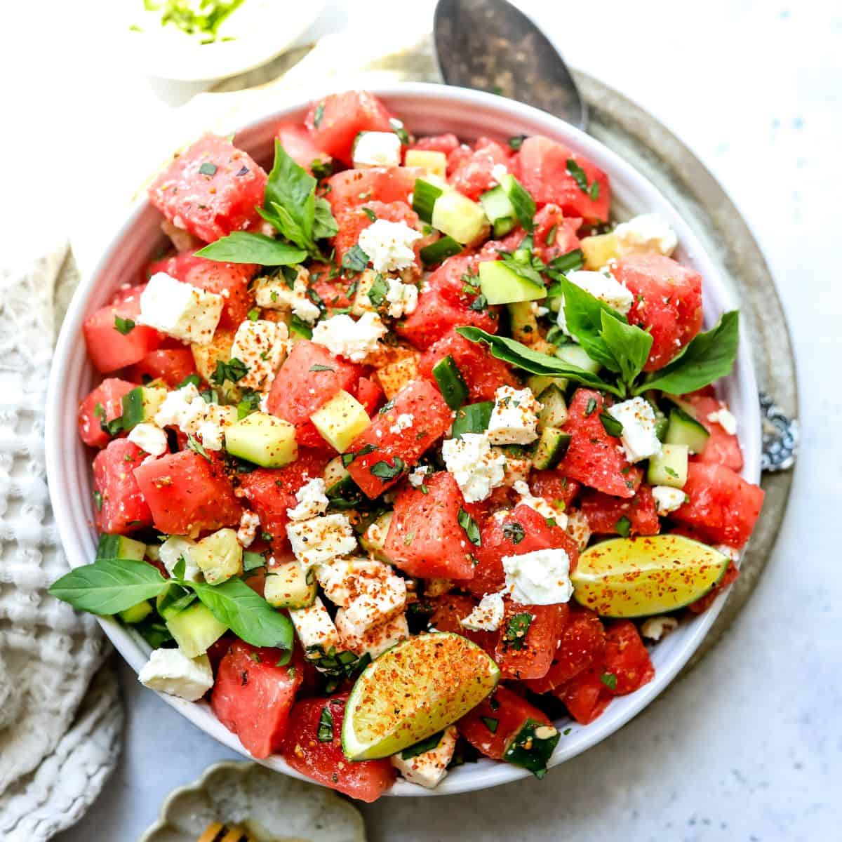 White bowl with ingredients mixed together to make watermelon salad with feta.