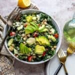 White bowl with kale and chickpeas, loads of veggies and dressing on the top.