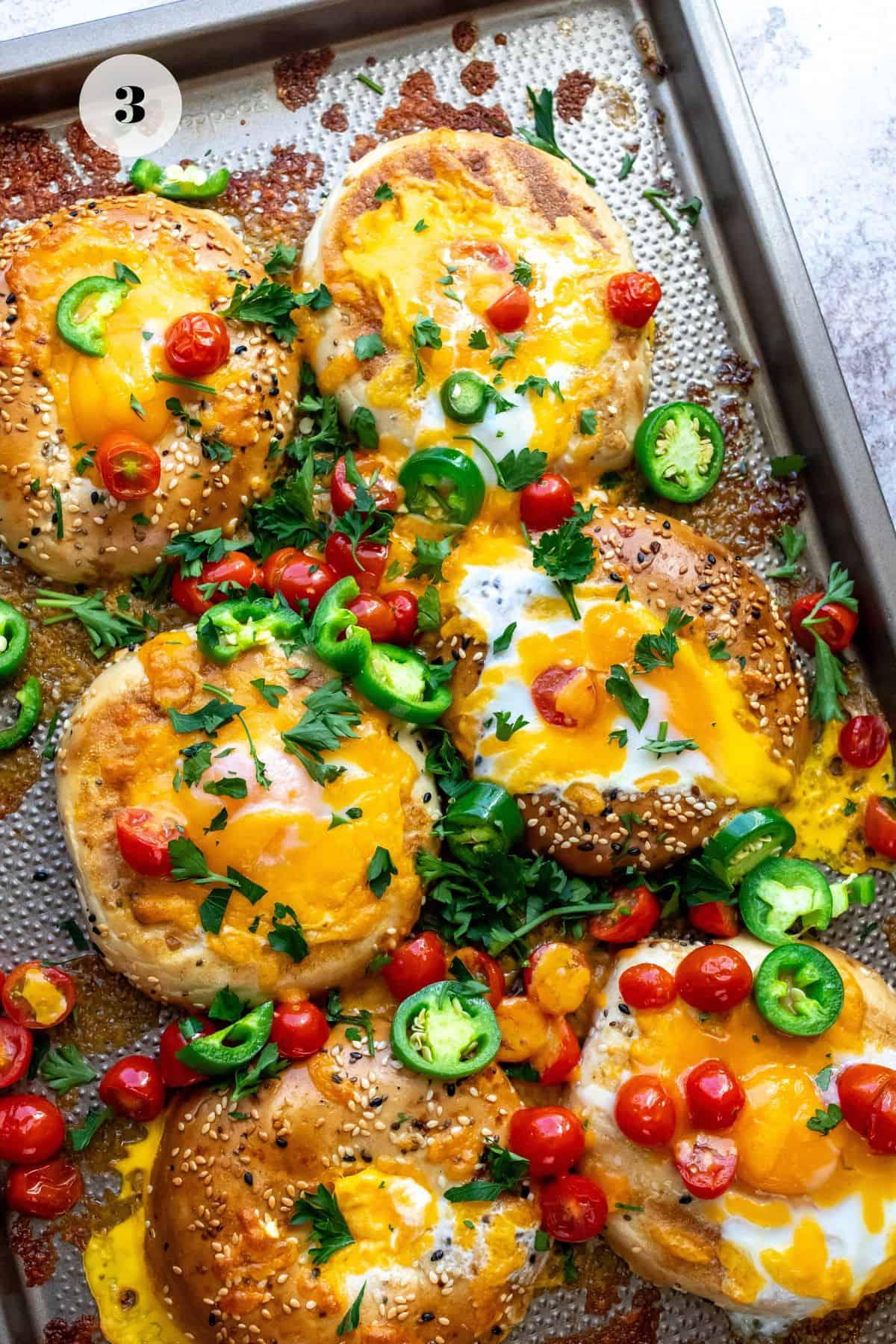 Bagels on a baking sheet with eggs in the hole. 