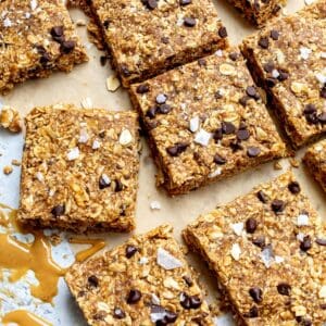 No bake granola bars on parchment paper with peanut butter on the side.