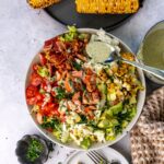 Salmon cobb salad in a bowl with a spoonful of dressing.