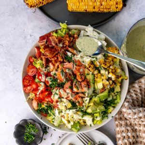 Salmon cobb salad in a bowl with a spoonful of dressing.