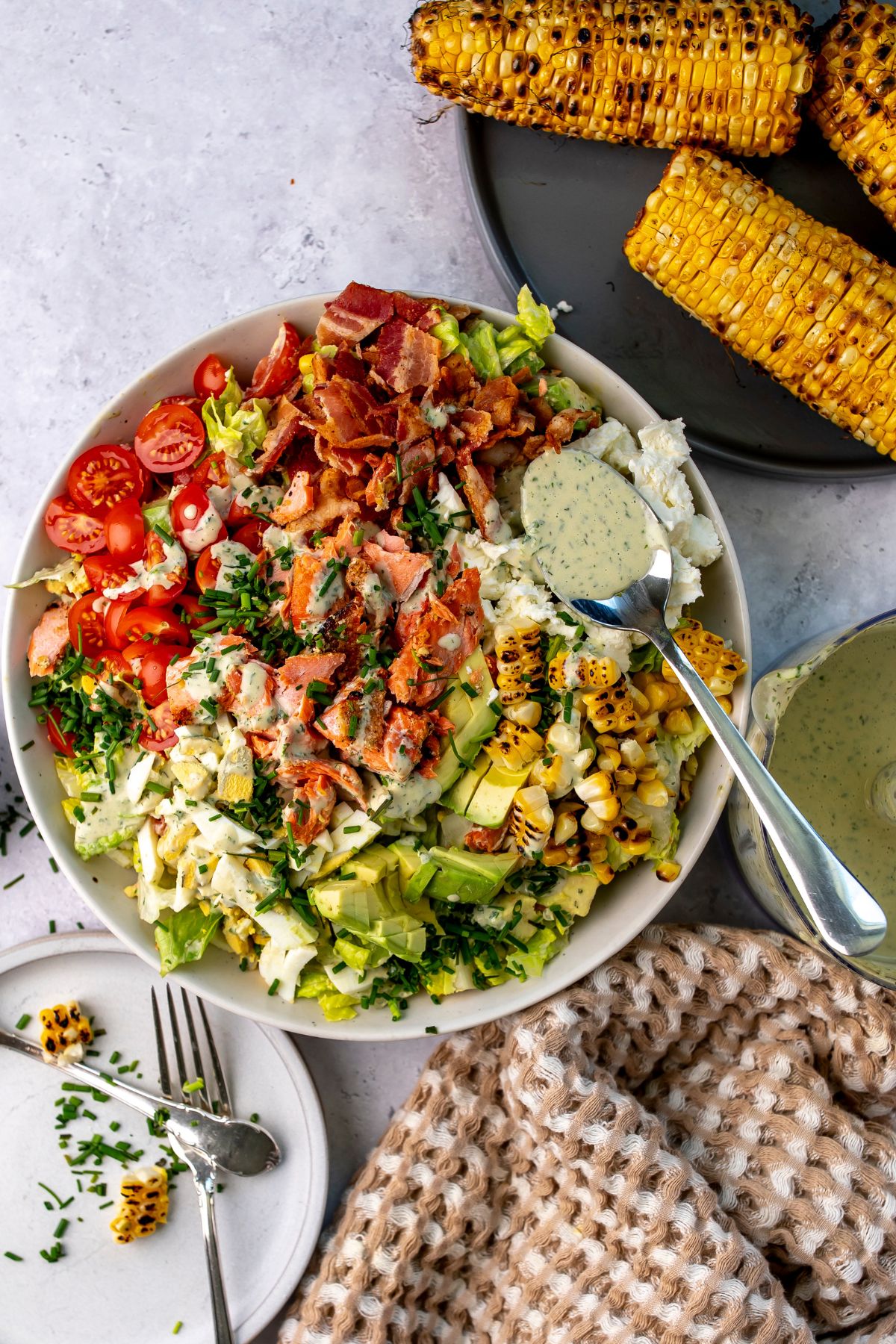 Salmon cobb salad in a bowl with a spoonful of dressing.