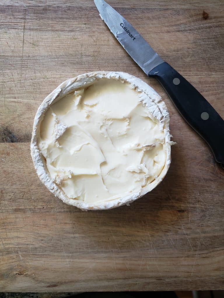 The top view of the brie with the top rind layer sliced off and removed.