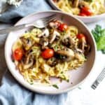 Pink bowl with pasta and tomatoes.