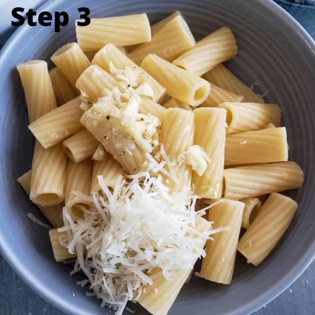 Finished pasta with pecorino over it about to be mixed together in a gray bowl. 