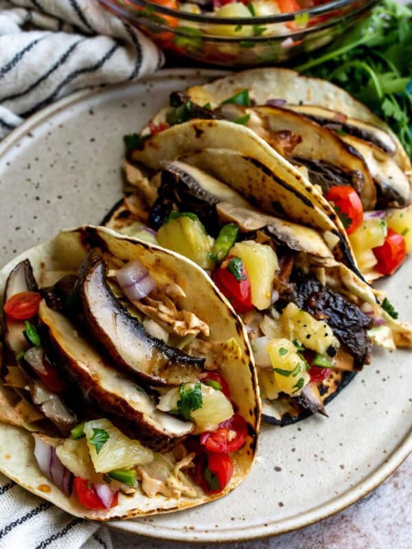 Tacos with mushrooms on a speckled plates.