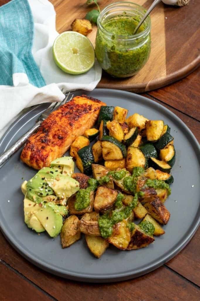 A grey plate full of food dressed with cilantro chimichurri.