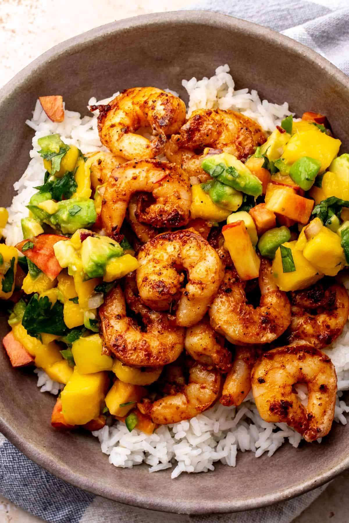 Grey bowl with blackened shrimp and mango salsa in it.