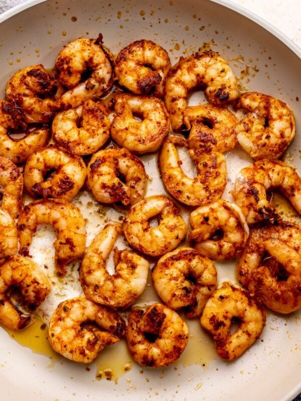 Blackened shrimp with butter in a grey pan.