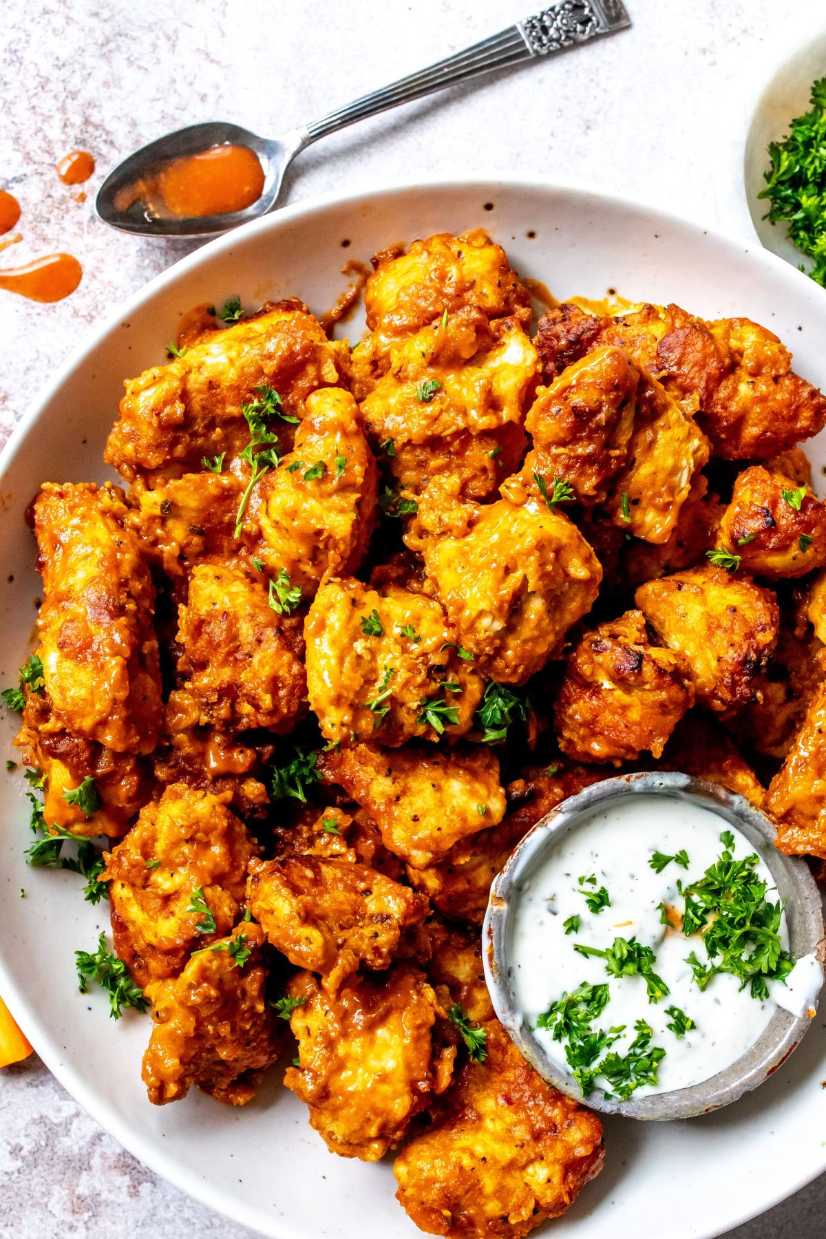 Boneless Wings in Air Fryer on a white plate with ranch on the side.