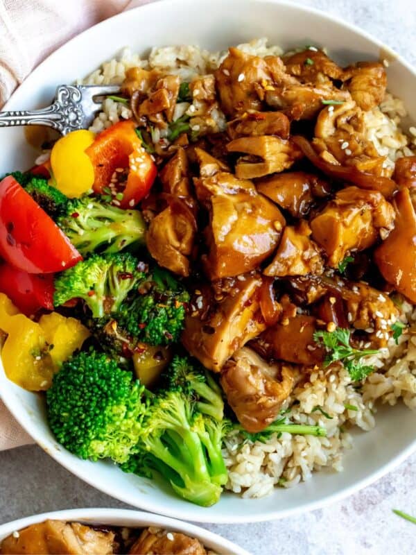 Teriyaki chicken thighs in a white bowl with a fork.