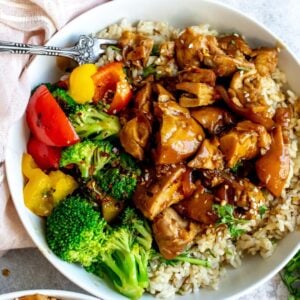 Teriyaki chicken thighs in a white bowl with a fork