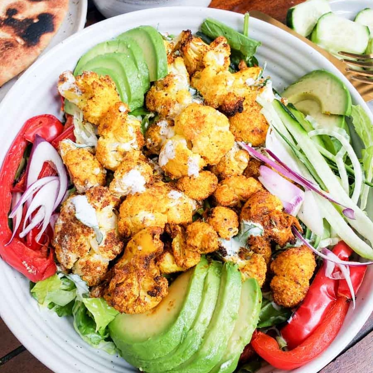 cauliflower Shawarma in a white bowl with fresh toppings. 