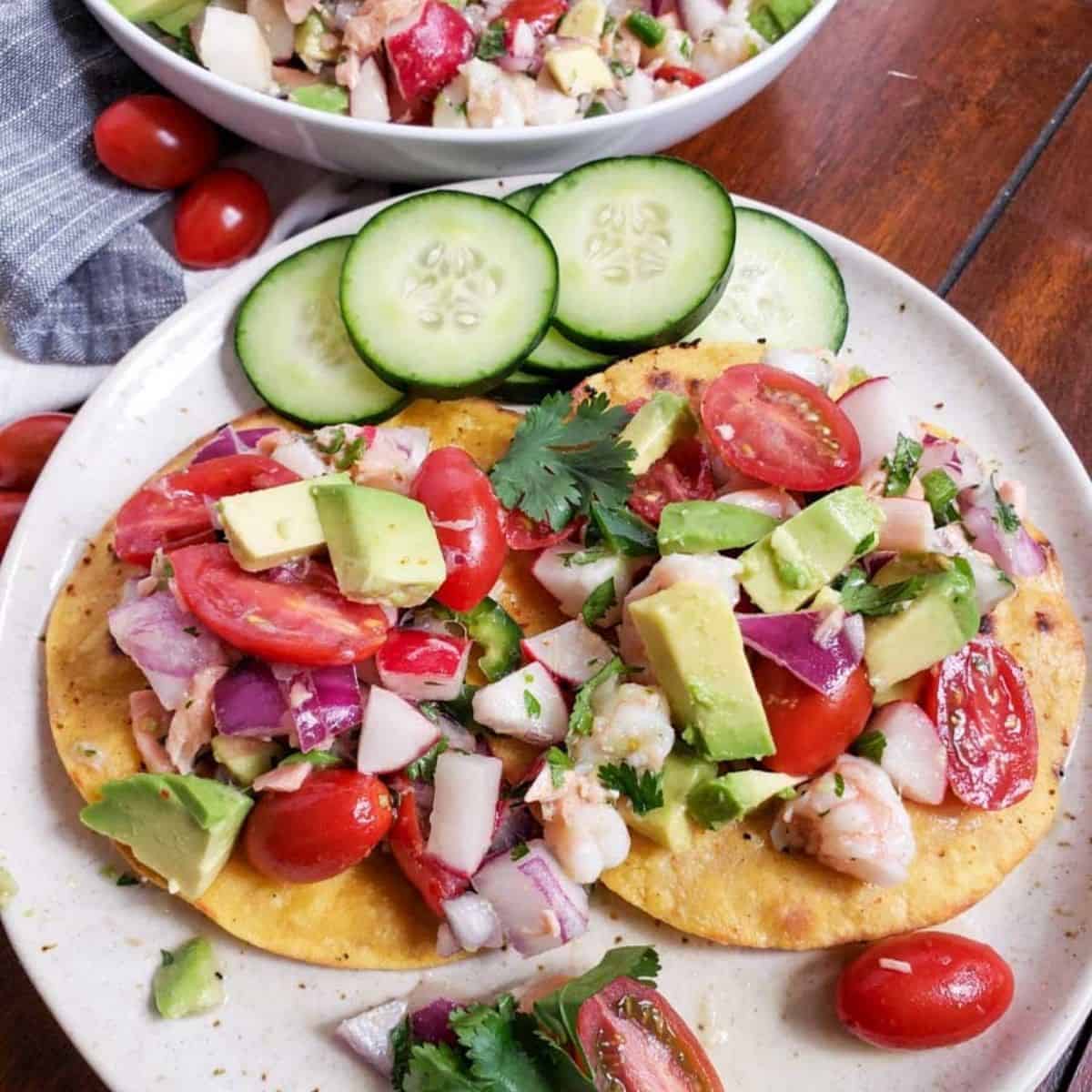 Shrimp and salmon ceviche on tostada and a white plate. 