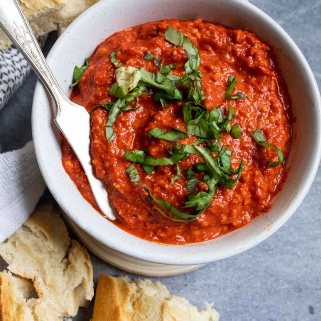 Red Pepper Dip in a white bowl with basil. 