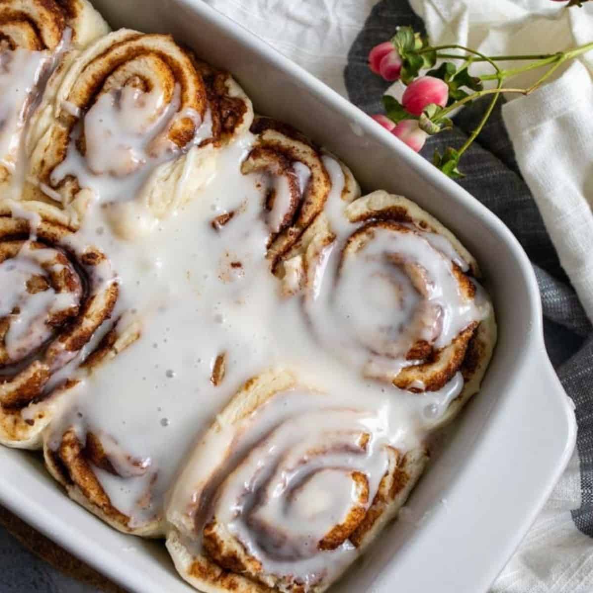 Baked vegan cinnamon rolls in a white dish. 