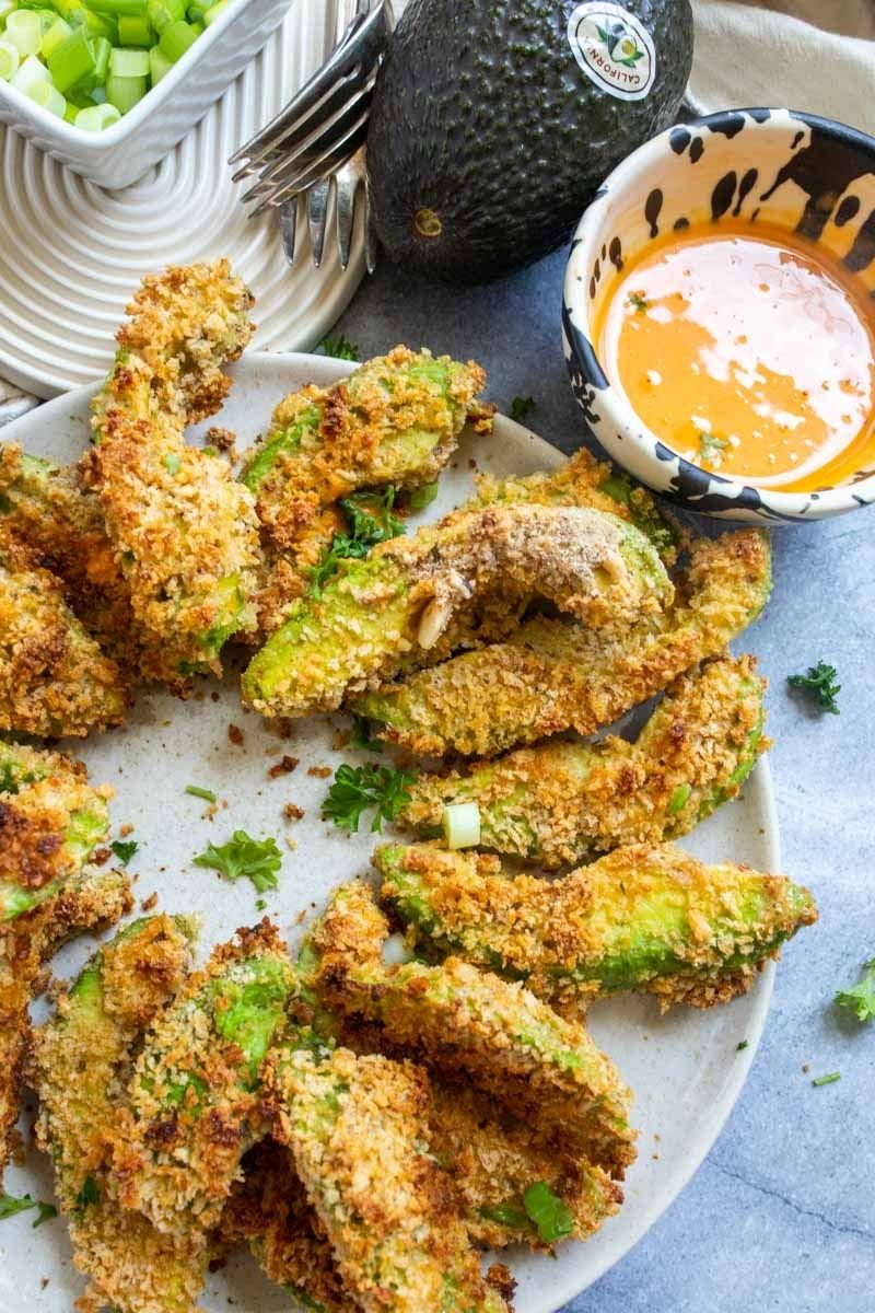 Avocado fries on a plate with dipping sauce. 