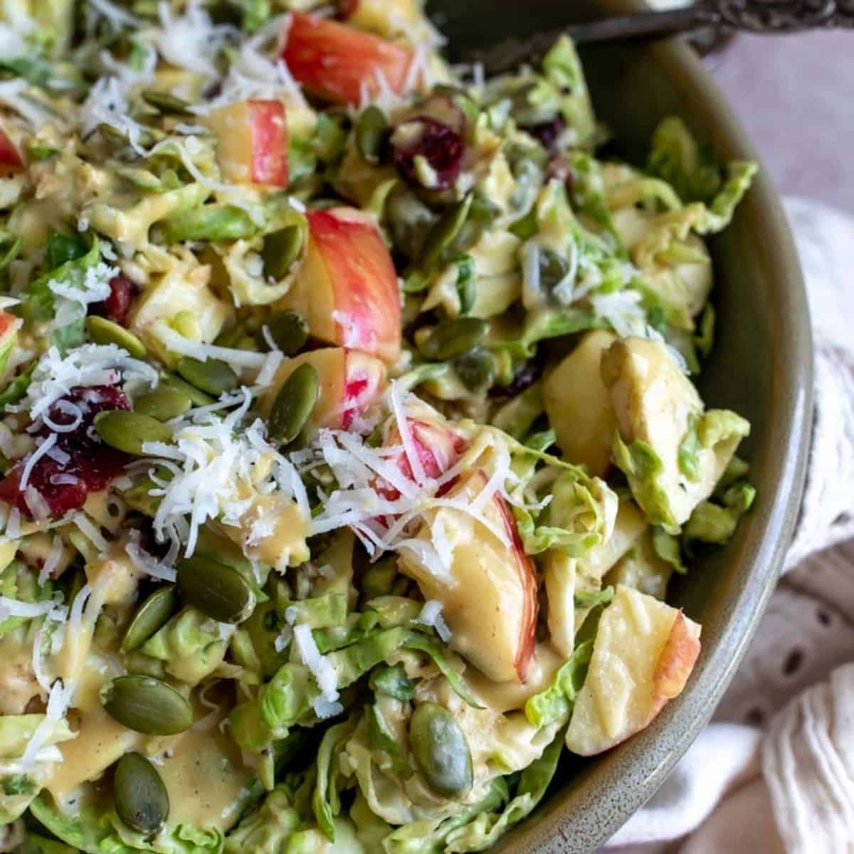 Close up photo of  brussel sprout salad in a green bowl. 