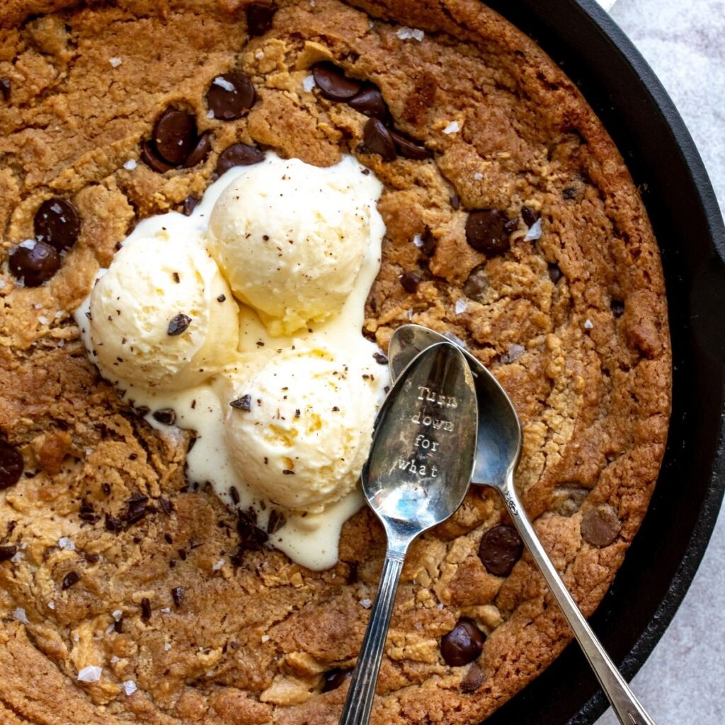 Cast iron cookie with ice cream and two spoons.