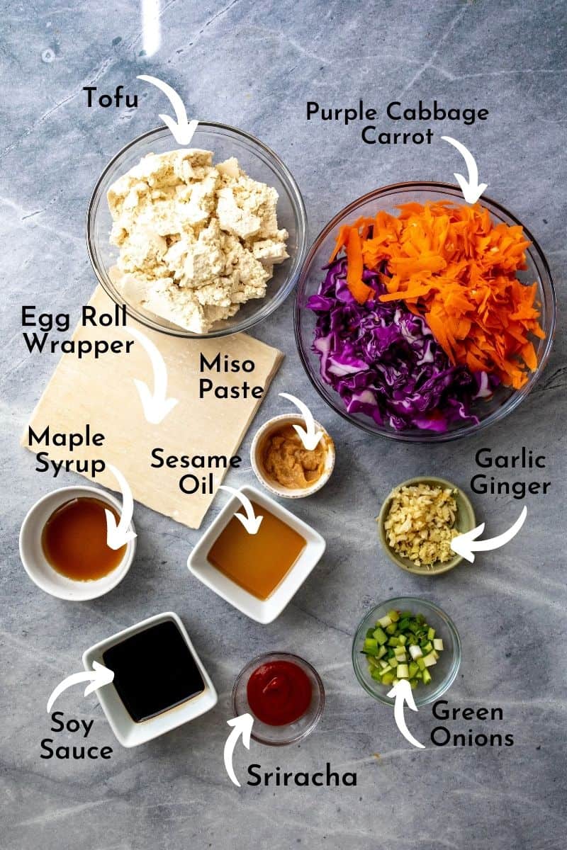 Egg roll ingredients on a grey board in bowls. 