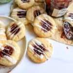 Raspberry Thumbprint Cookies on a white plate with jam on the side.