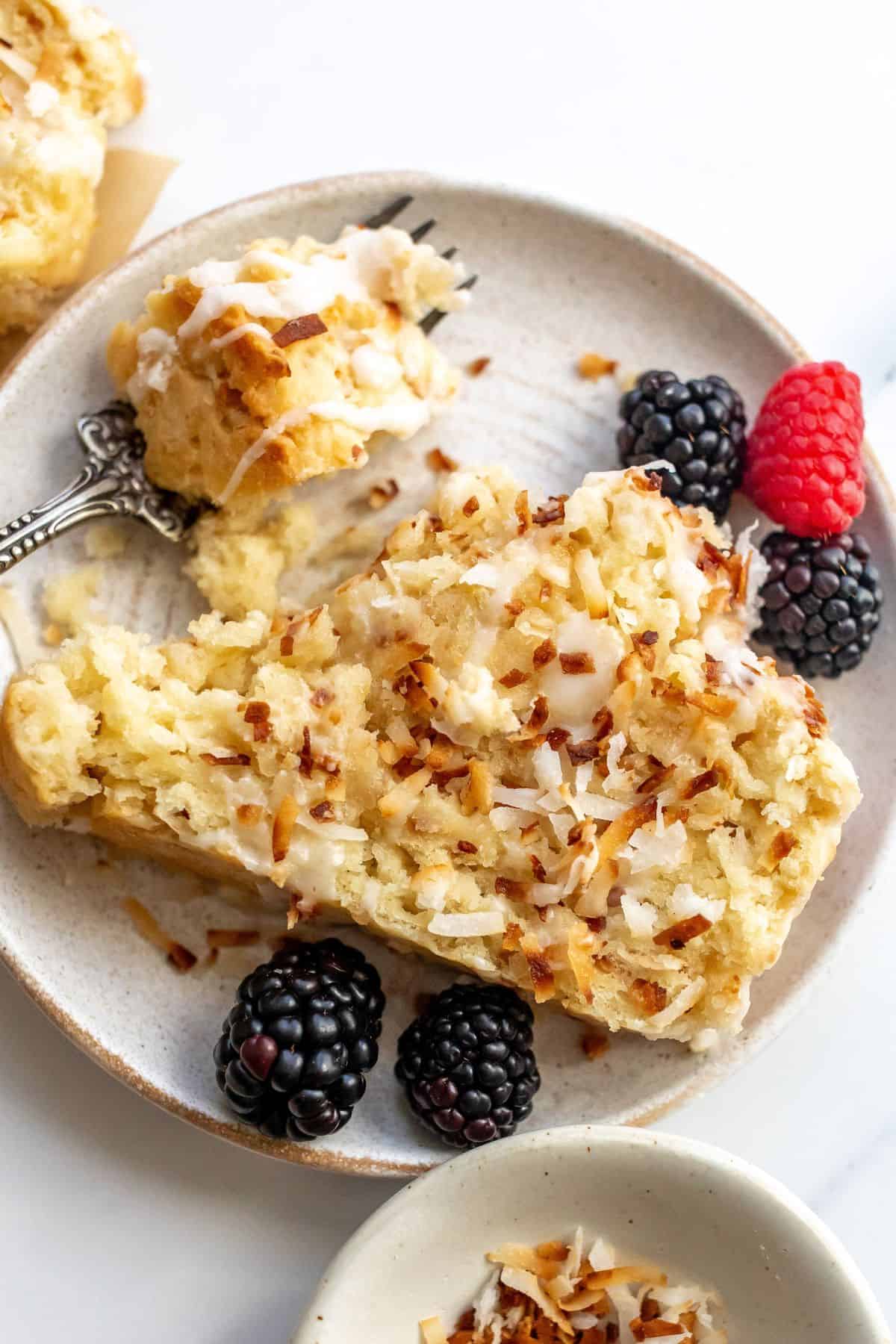 Coconut bread on a white plate with berries and a fork to the side.