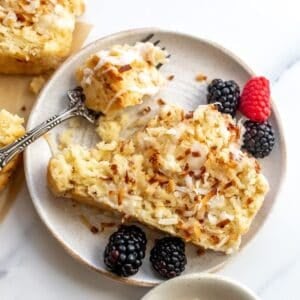 Coconut bread on a white plate with berries and a fork to the side.