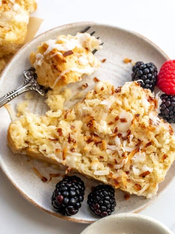 Coconut bread on a white plate with berries and a fork to the side.