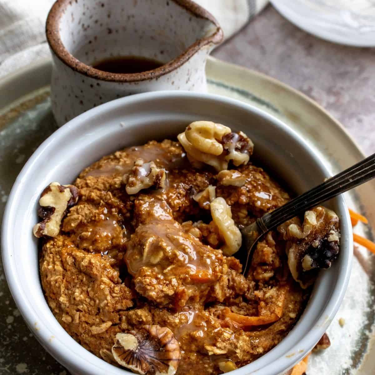 Vegan Carrot Cake Baked Oats in a white bowl with spoon. 