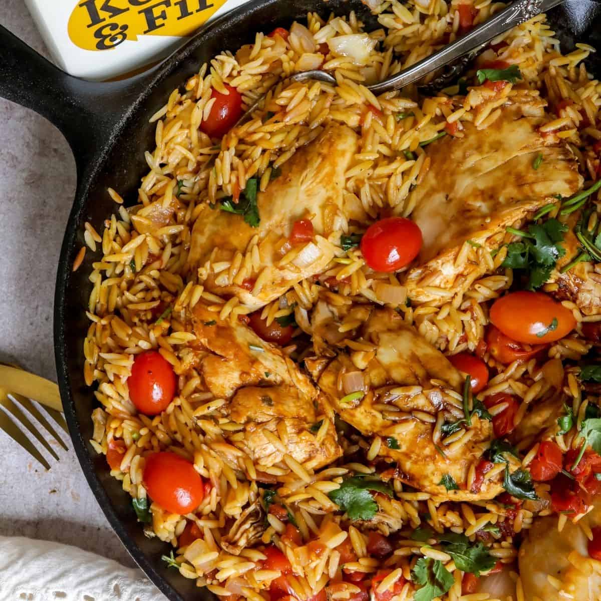 Chicken and Orzo in a skillet with serving spoon.
