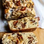 Date nut bread on a cutting board with pieces standing up and some laying over.