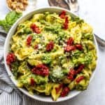 Tortellini with pesto in a white bowl up close.