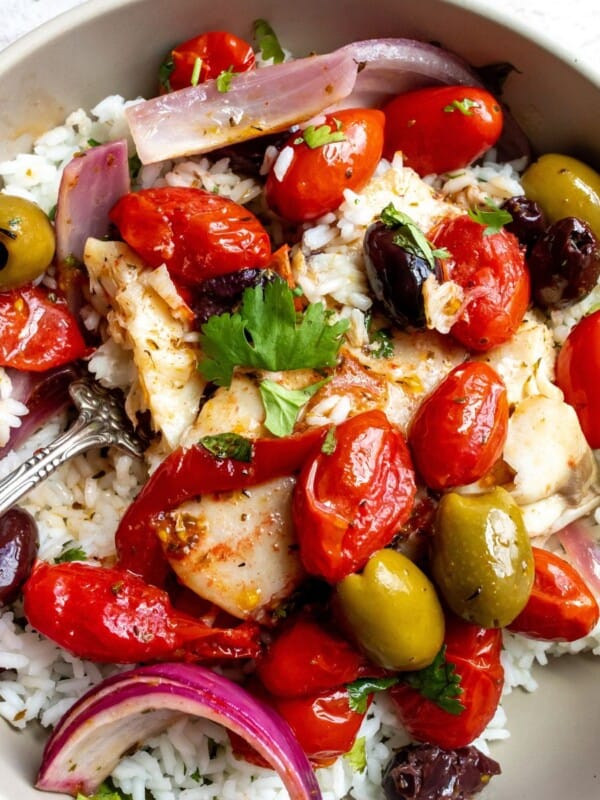 Baked Mediterranean fish in a grey bowl with olives.