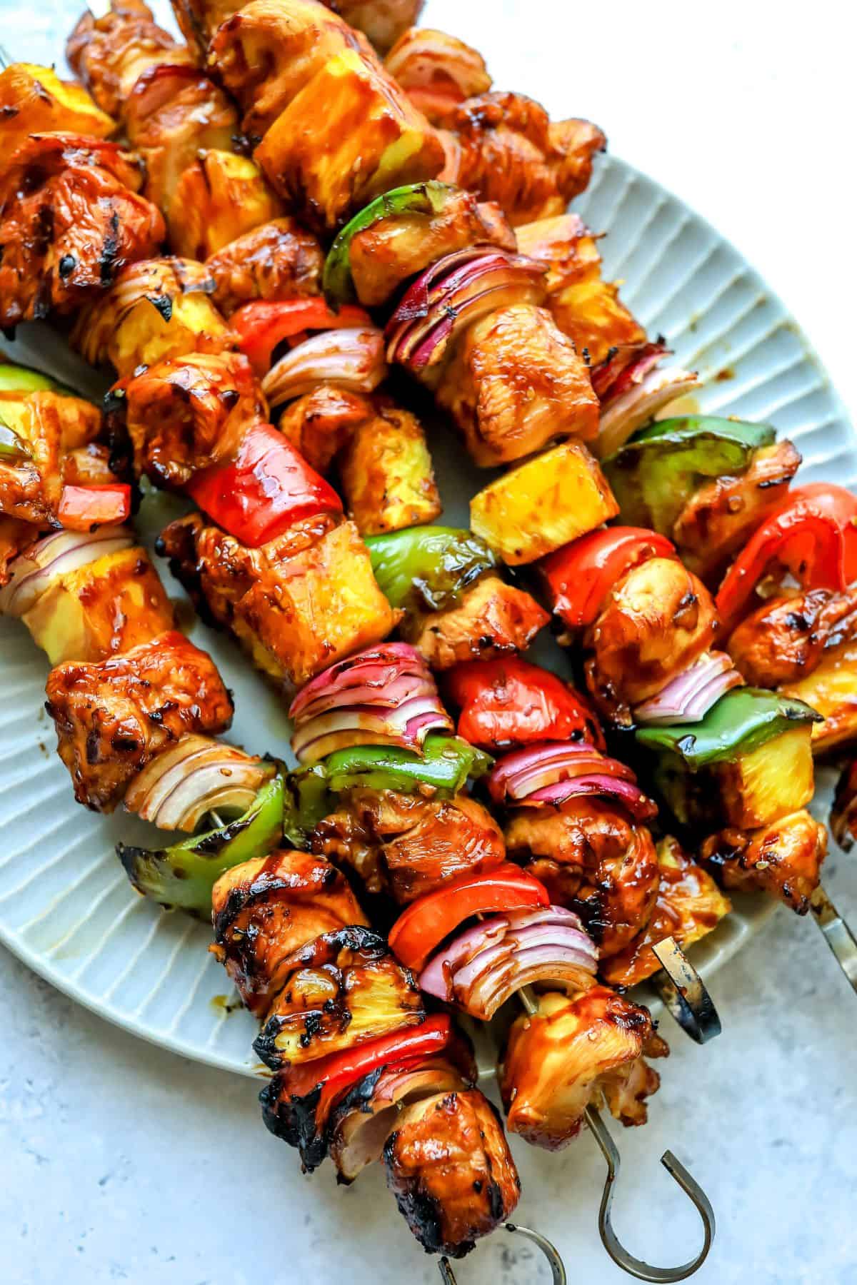 Teriyaki Chicken Skewers on a plate with metal skewers.