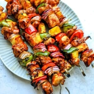 Teriyaki Chicken Skewers on a plate with metal skewers.