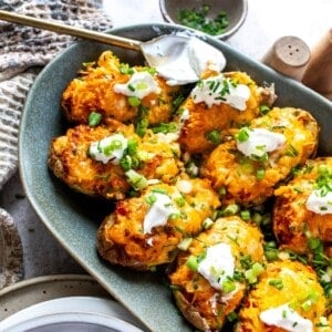Green serving plate with twice baked potatoes an sour cream on tip.