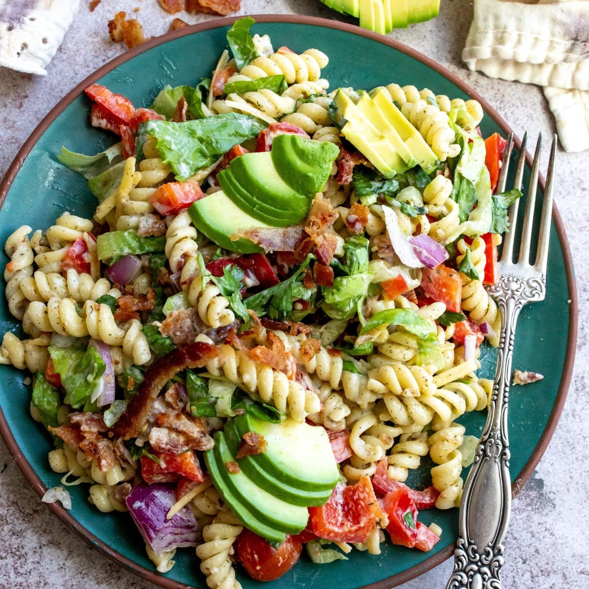 BLT pasta salad on a green plate with a fork.