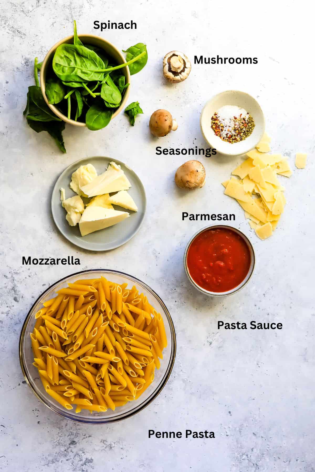 Baked Penne Pasta With Mozzarella ingredients on a counter in bowls. 