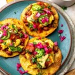 Breakfast Tostada on a green plate with toppings.