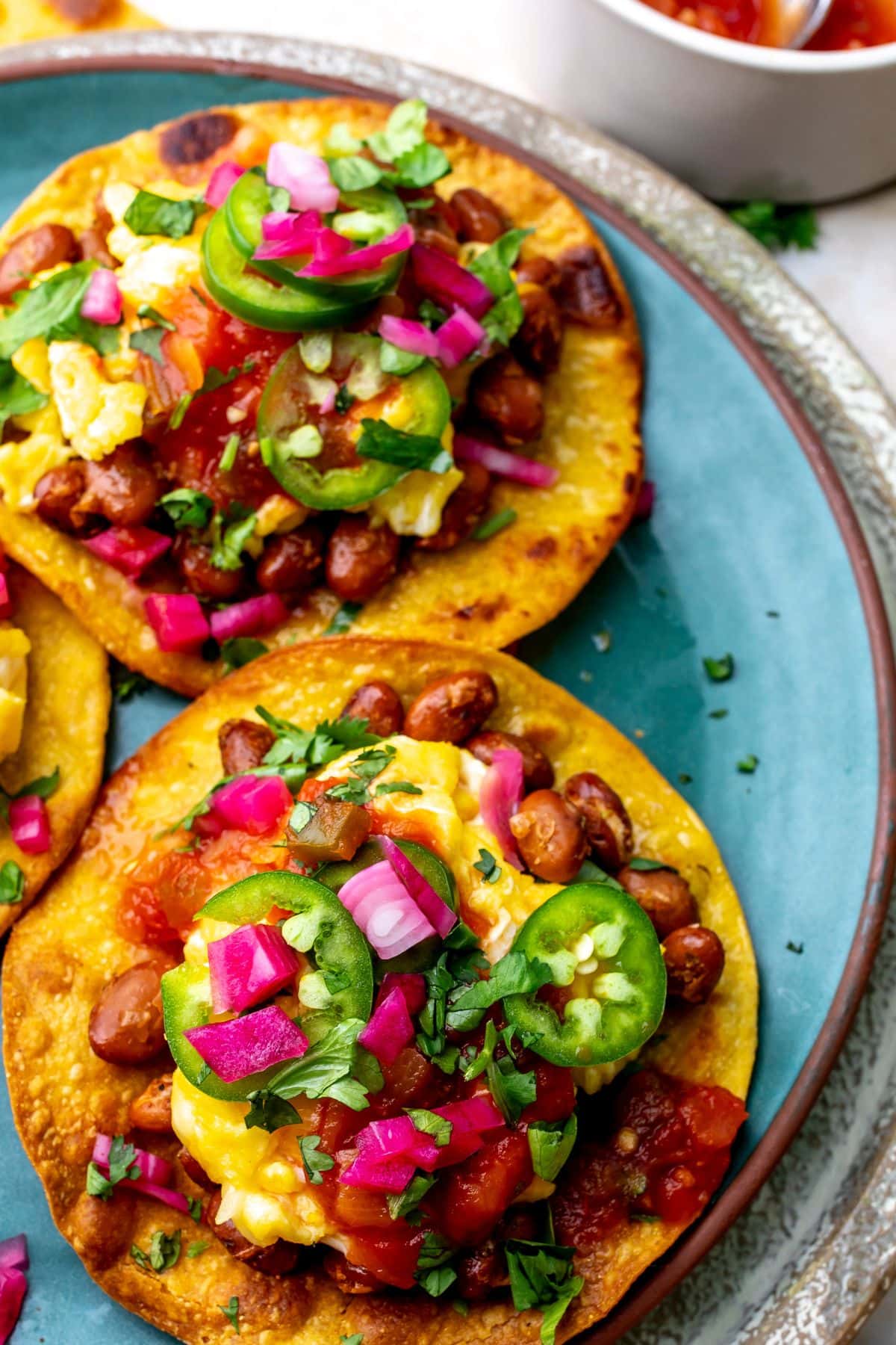 Breakfast Tostada on a green plate with toppings.