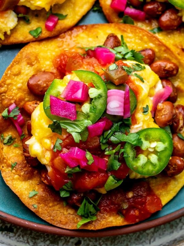 Breakfast Tostada on a green plate with toppings, up close photo.