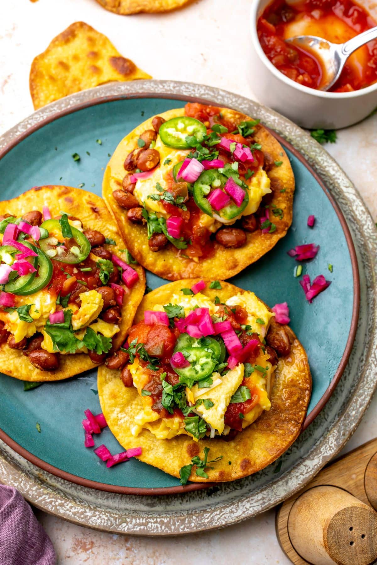 Breakfast Tostada on a green plate with toppings.