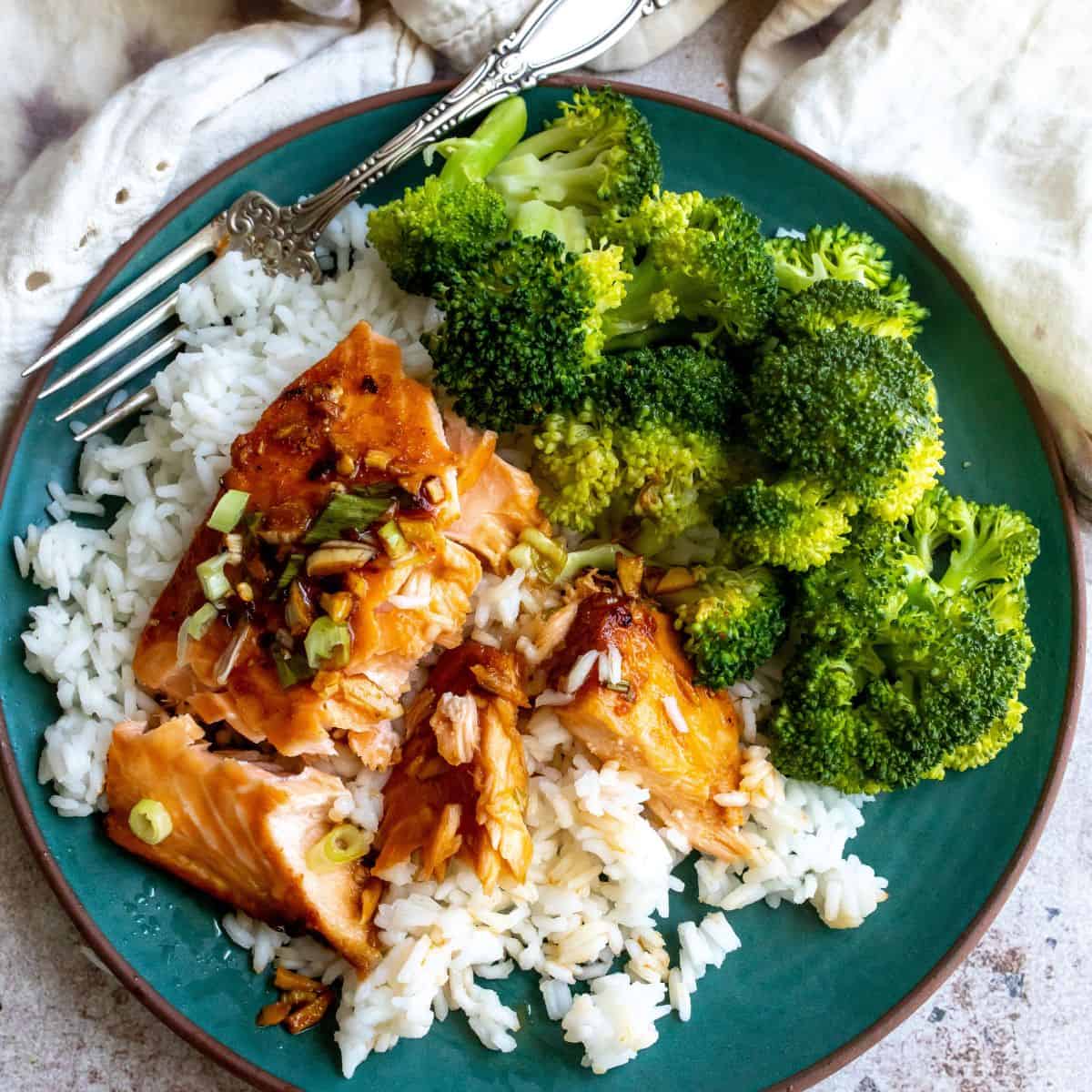 Firecracker Salmon on a green plate with rice and broccoli. 